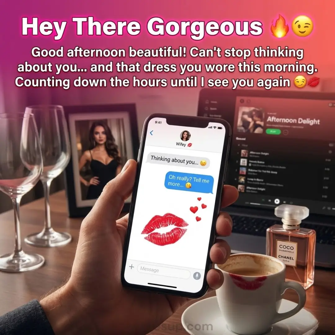 A hand holds a smartphone displaying flirty text messages over a warm, romantic desk featuring a lipstick-stained ceramic mug and luxury perfume. The scene is bathed in a soft pink glow with elegant wine glasses and a framed portrait.